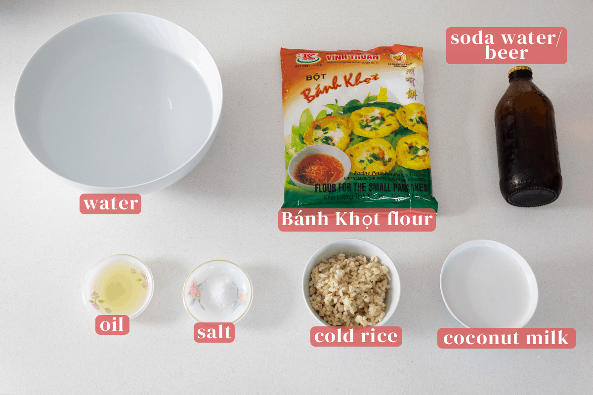 A bowl of water along with a bag of banh khot flour and dishes of oil, salt, day old rice and coconut milk.