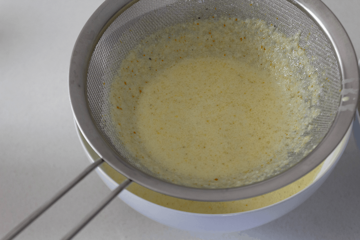 Banh Khot batter in a bowl with a sieve on top.