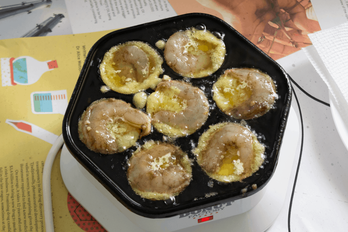 Banh khot cooking in a donut hole maker.