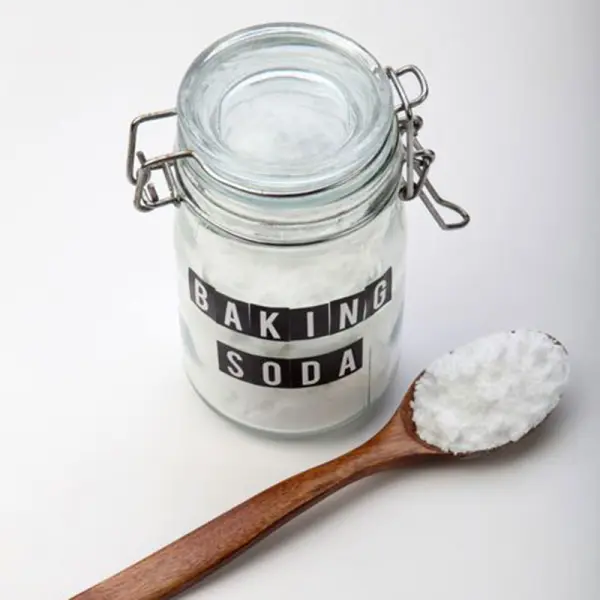 Lọ thủy tinh đựng baking soda và một muỗng gỗ có đựng baking soda.