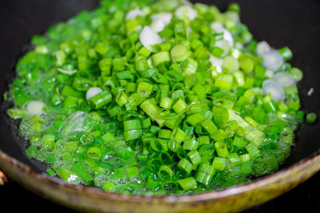 scallions in hot oil inside of a nonstick pan