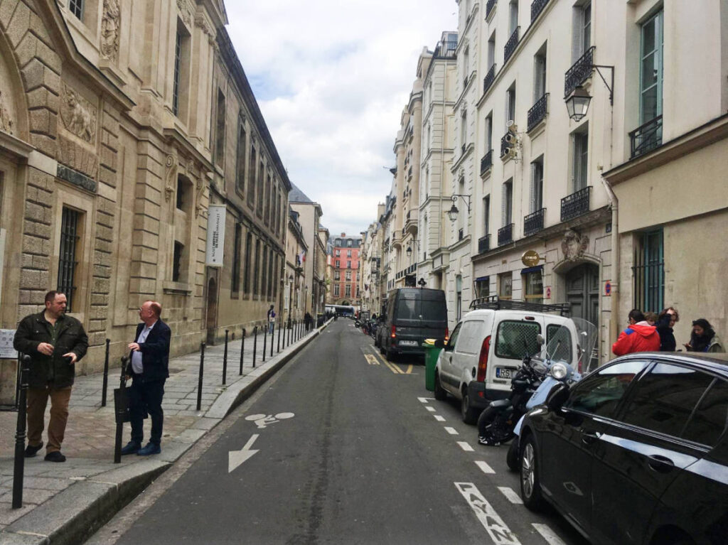 People and vehicles on a narrow Marais street