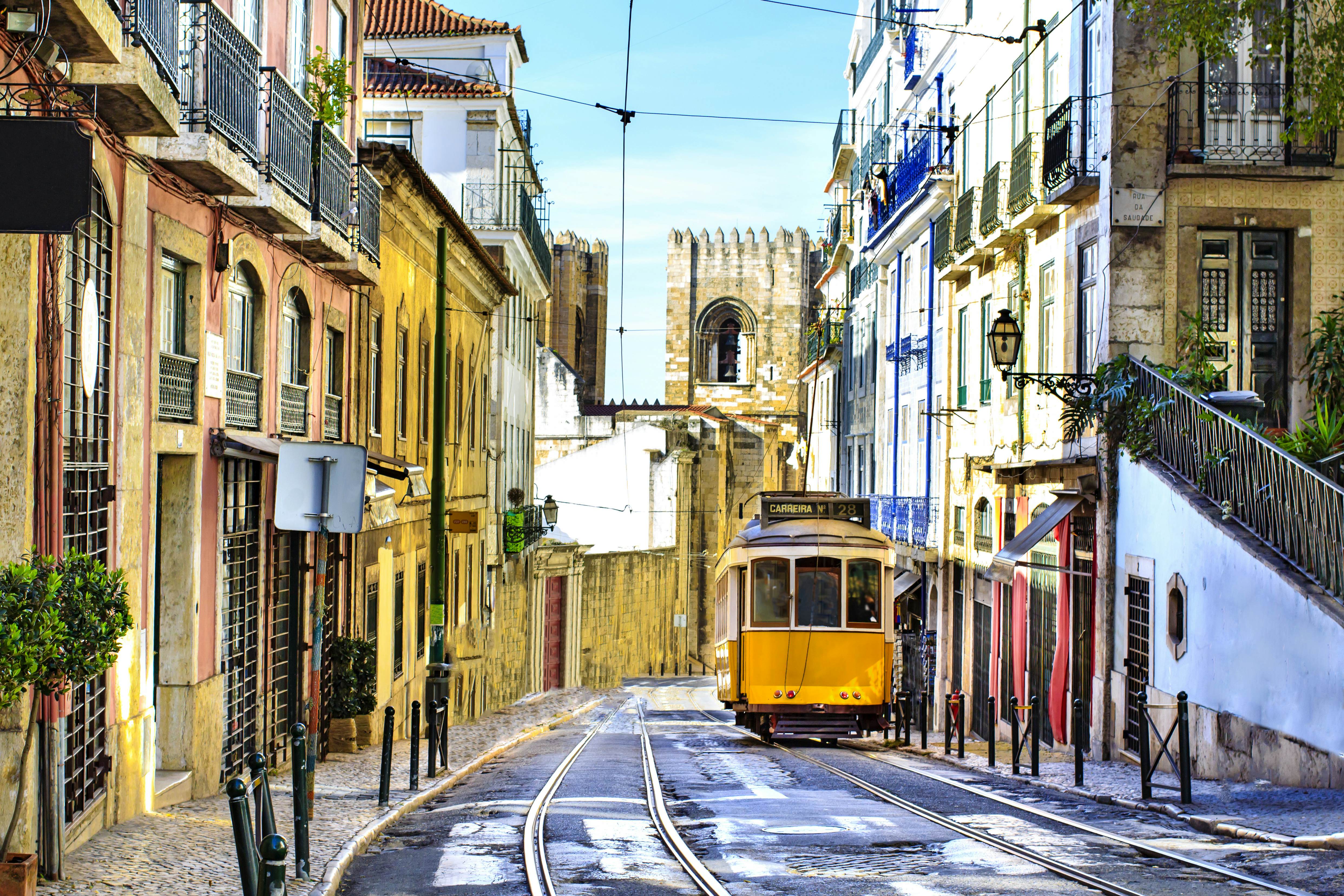 A yellow tram travels down an empty street