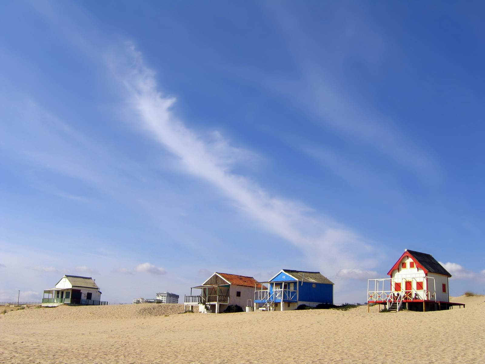 Wooden beach huts dot a golden sandy beach